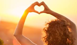 Person staring at the horizon making a heart shape with their hands